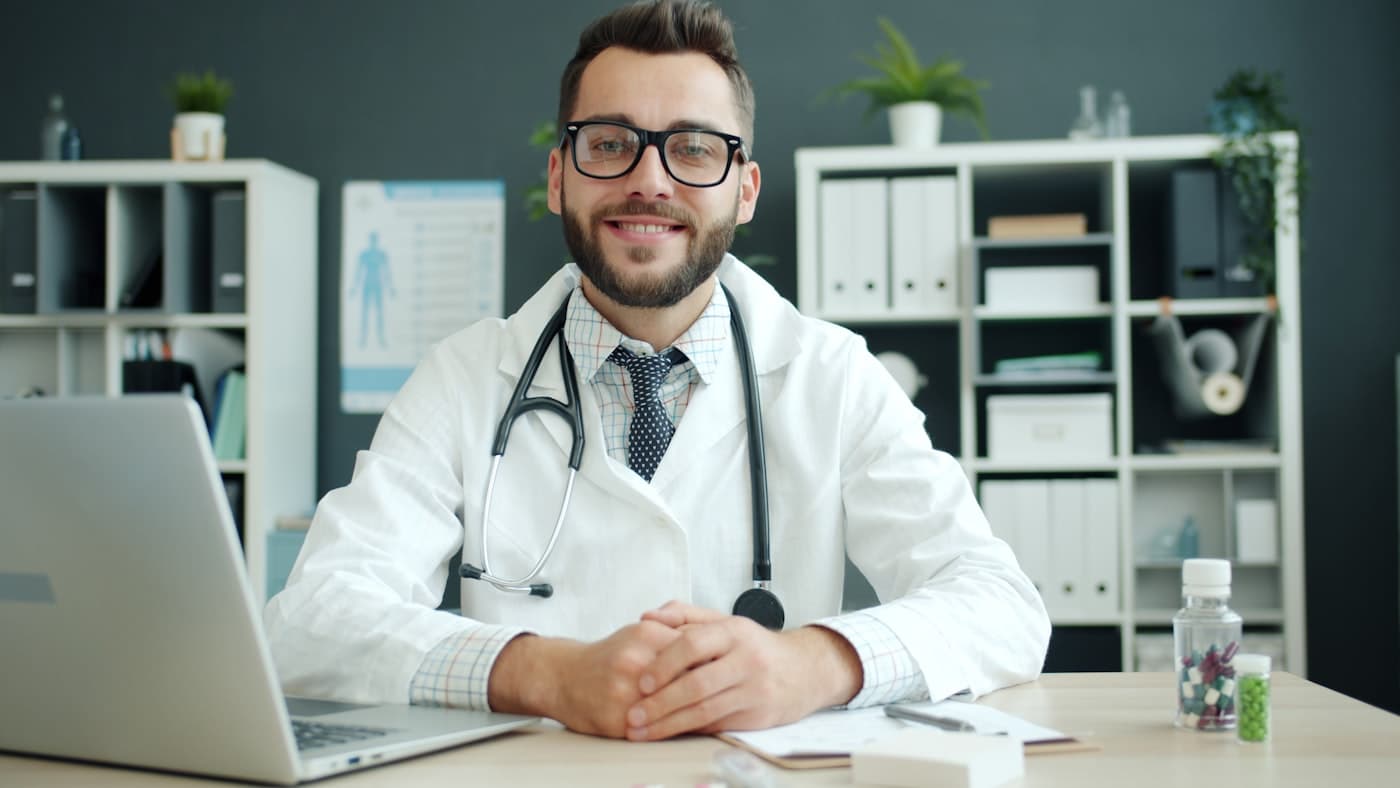 Praticien souriant à son bureau, devant son ordinateur